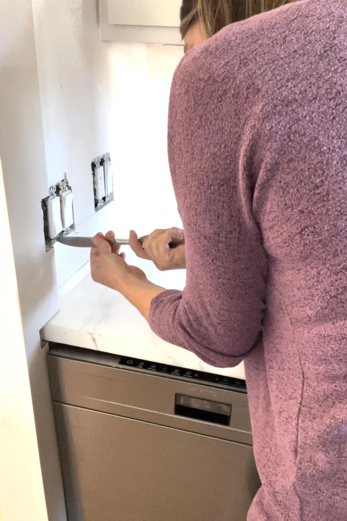 Using a butter knife as a screwdriver.